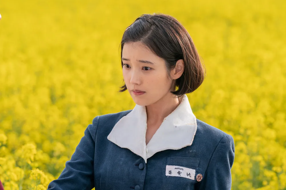 IU as Oh Ae-sun standing in a field of yellow canola flowers in When Life Gives You Tangerines