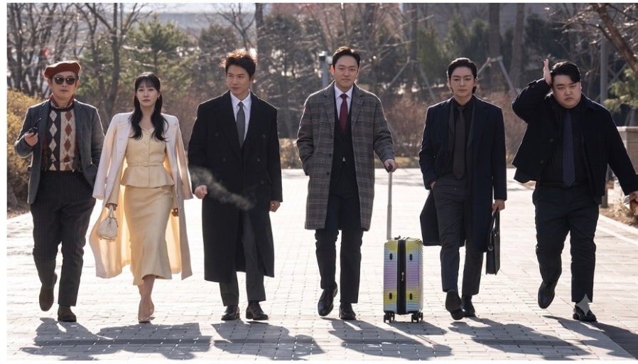 The main cast of the Korean drama The Apartment Job, including actors Ji Sung and Ha Yoon-kyung, walking side-by-side in suits and coats on an outdoor pathway